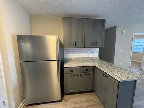A kitchen with a stainless steel refrigerator and cabinets.