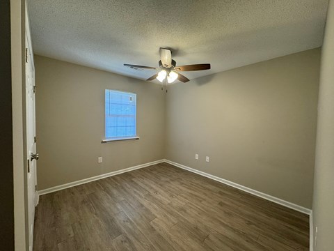 A room with a ceiling fan and a window with blinds.