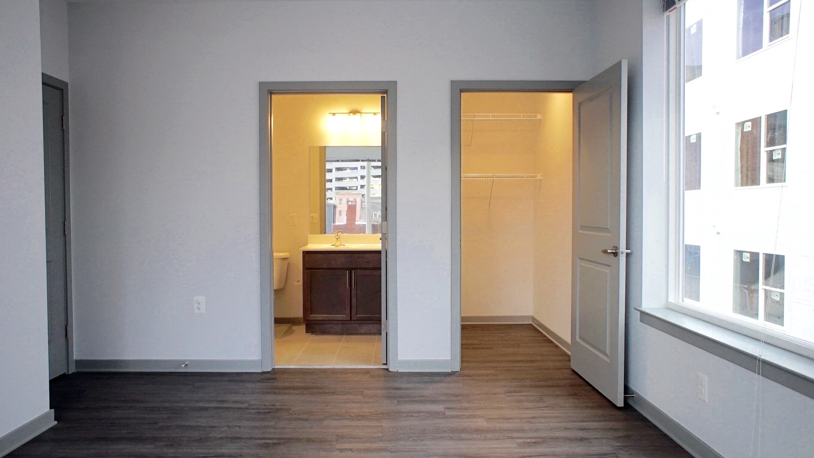 an empty living room with a door open to a bathroom and a closet