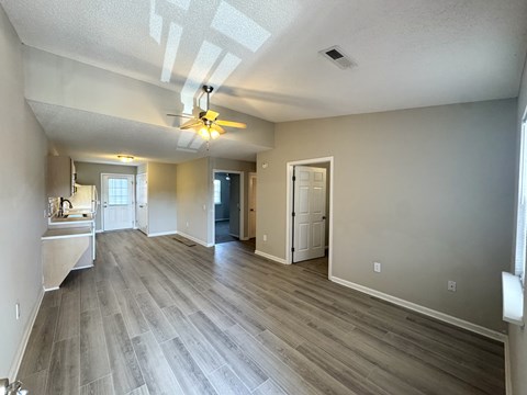 A spacious room with a ceiling fan and lighting fixture.