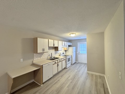 A kitchen with white cabinets and a window.