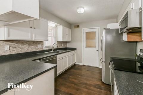 a kitchen with black counter tops and white cabinets and stainless steel appliances
