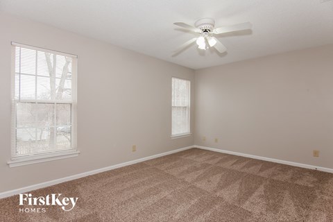 a spacious living room with carpet and a ceiling fan