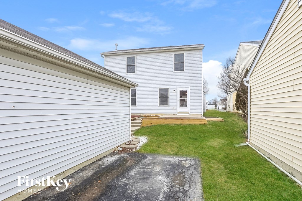 the back of a white house with a yard and a garage