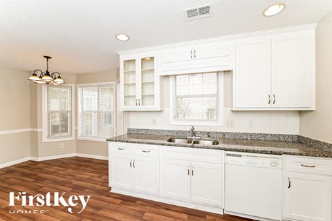 A kitchen with white cabinets and a granite countertop.