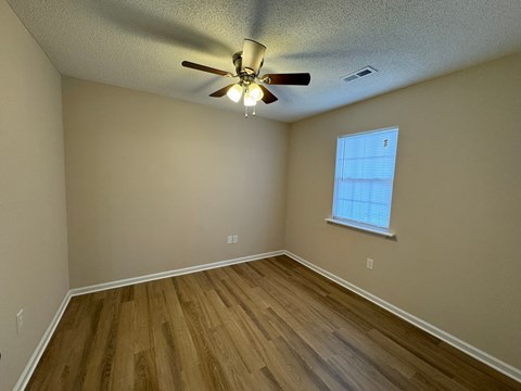 an empty bedroom with hardwood floors and a ceiling fan