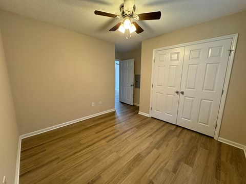 an empty living room with wood floors and a ceiling fan