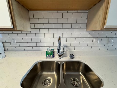 A kitchen sink with a green box of wipes on top of it.