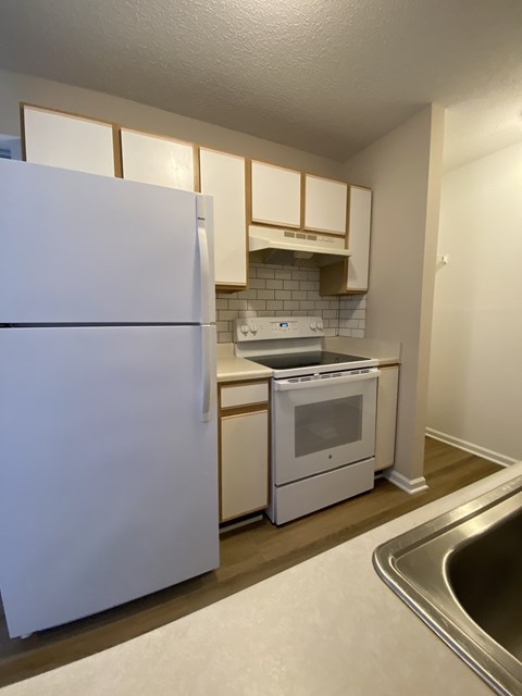 A white refrigerator is in a kitchen with a stove and oven.