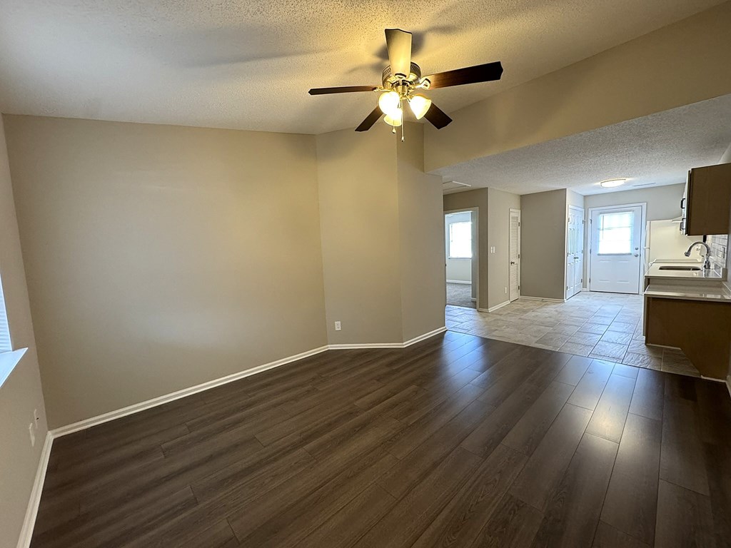 A room with a ceiling fan and wooden flooring.
