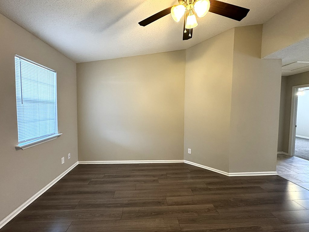 A room with a ceiling fan and wooden flooring.