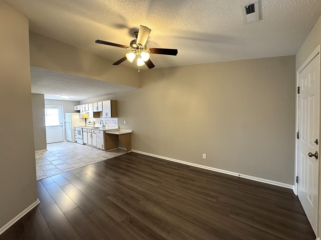 A room with a ceiling fan and wooden flooring.