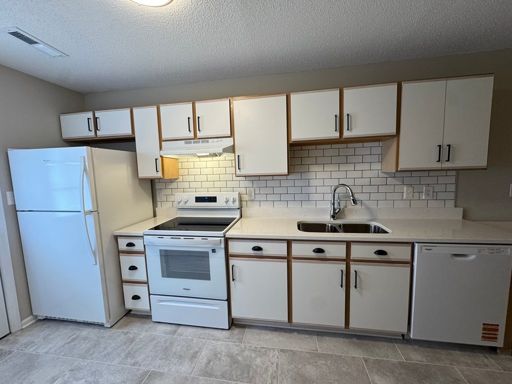 A kitchen with white appliances and cabinets.