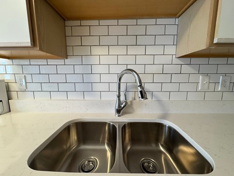 A kitchen sink with a double faucet.