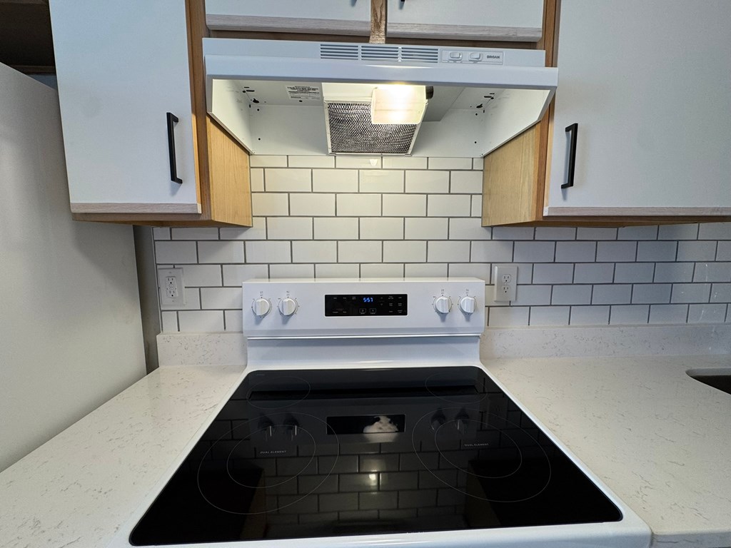 A white kitchen with a black stove top.