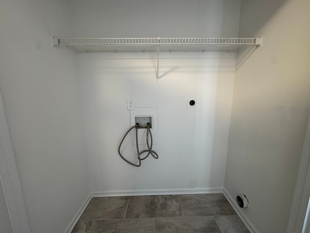 A white wall with a tile floor and a white shelf above it.