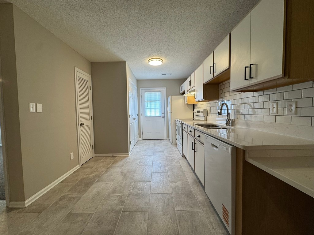 A kitchen with white appliances and wooden cabinets.