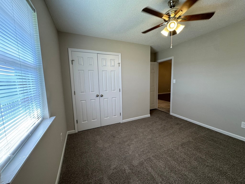 A room with a ceiling fan and a carpeted floor.