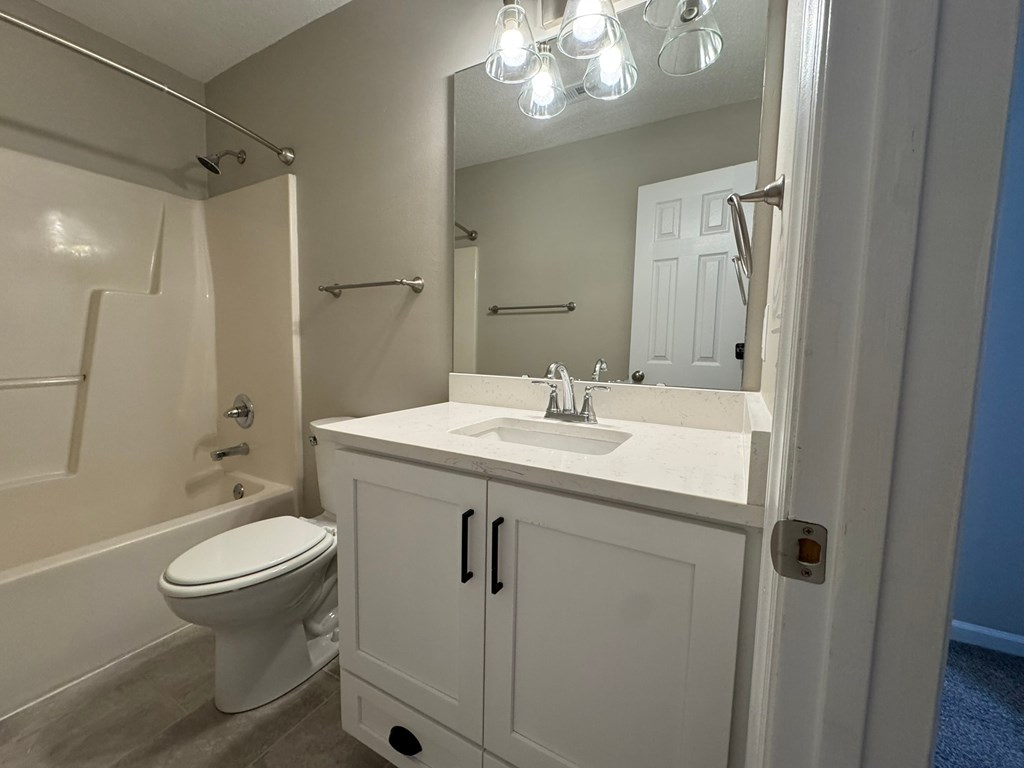 A white bathroom with a toilet, sink, and mirror.