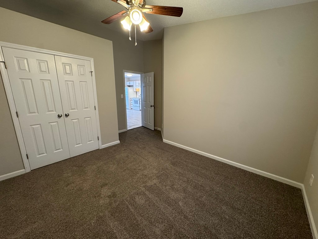 A room with a ceiling fan and carpeted floor.