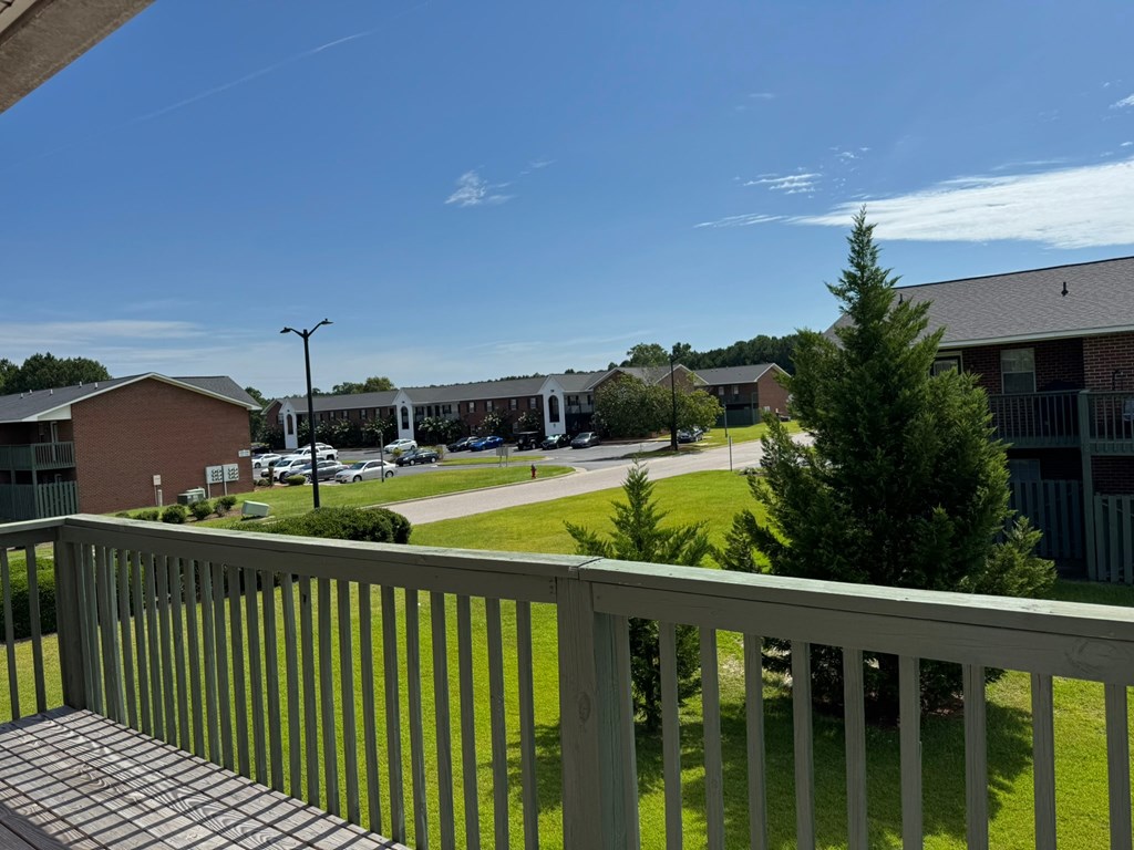 A view from a balcony overlooking a parking lot and buildings.