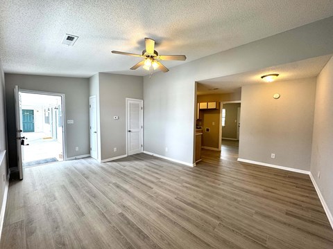 A spacious room with a ceiling fan and lighting fixture.