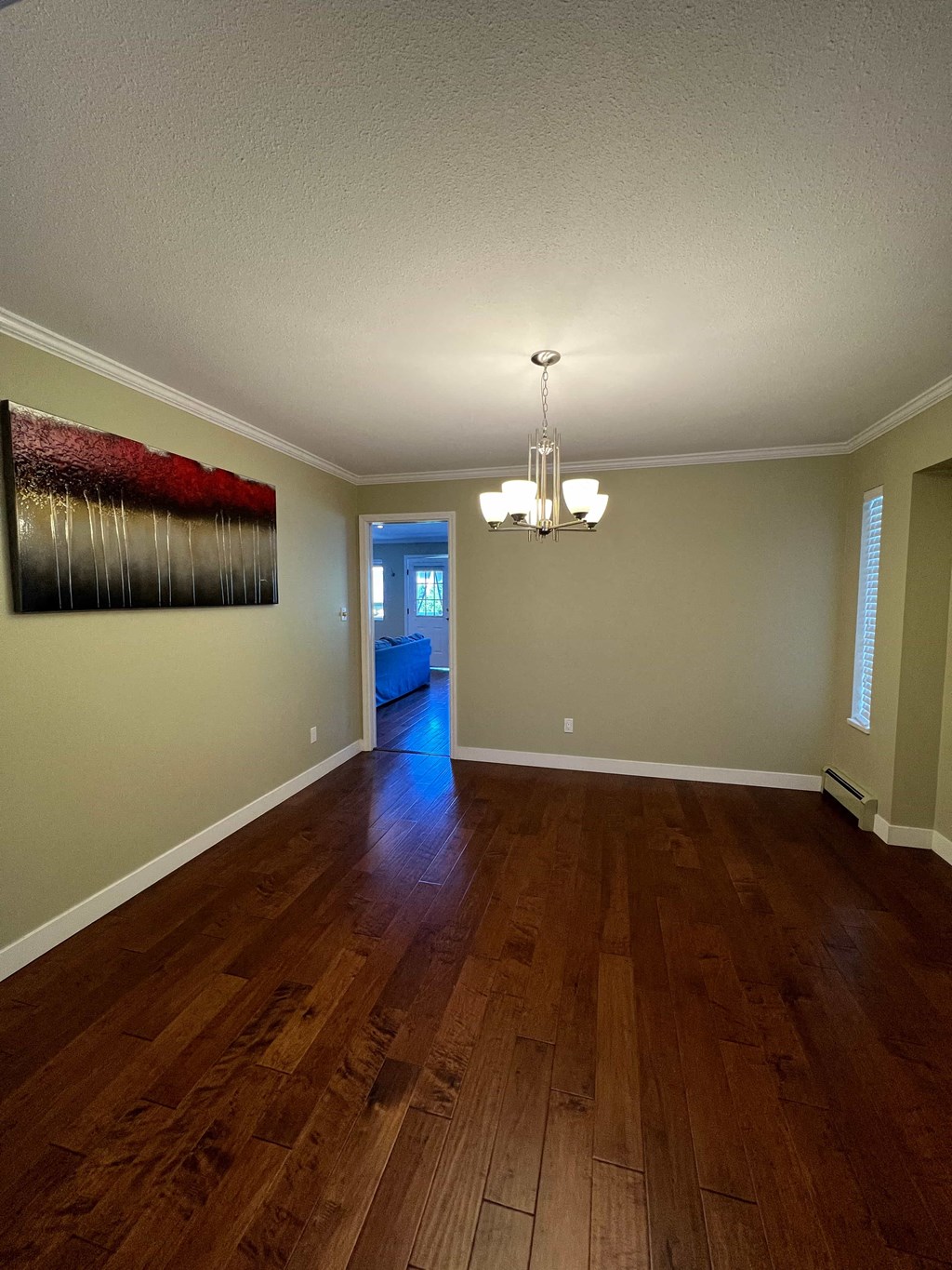 a living room with wood floors and a painting on the wall