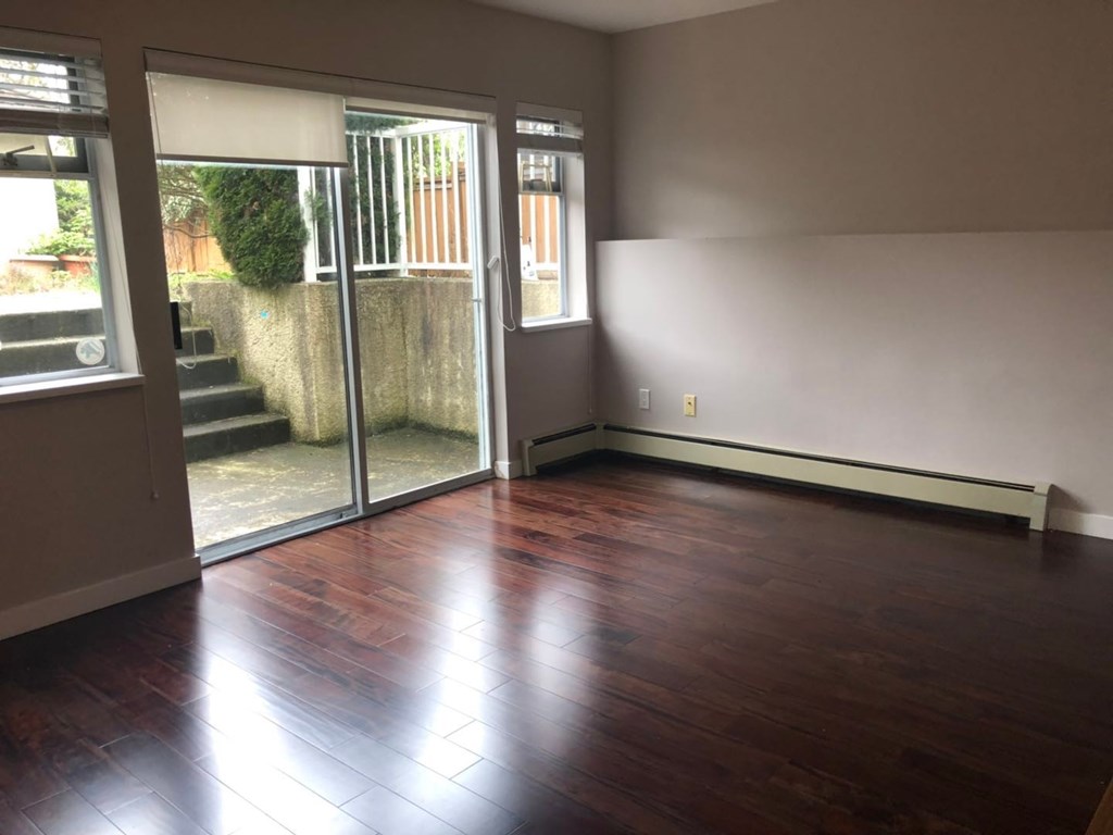 an empty living room with wooden floors and a sliding glass door