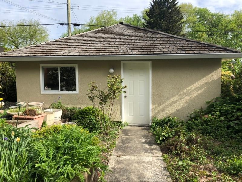 a small tan house with a white door and a sidewalk