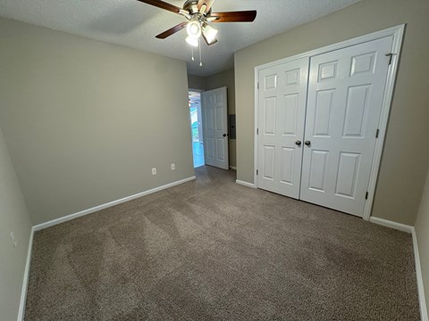 an empty living room with carpet and a ceiling fan