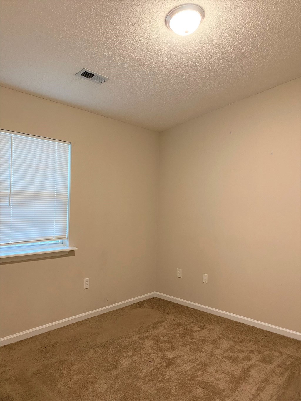 an empty living room with a window and carpet
