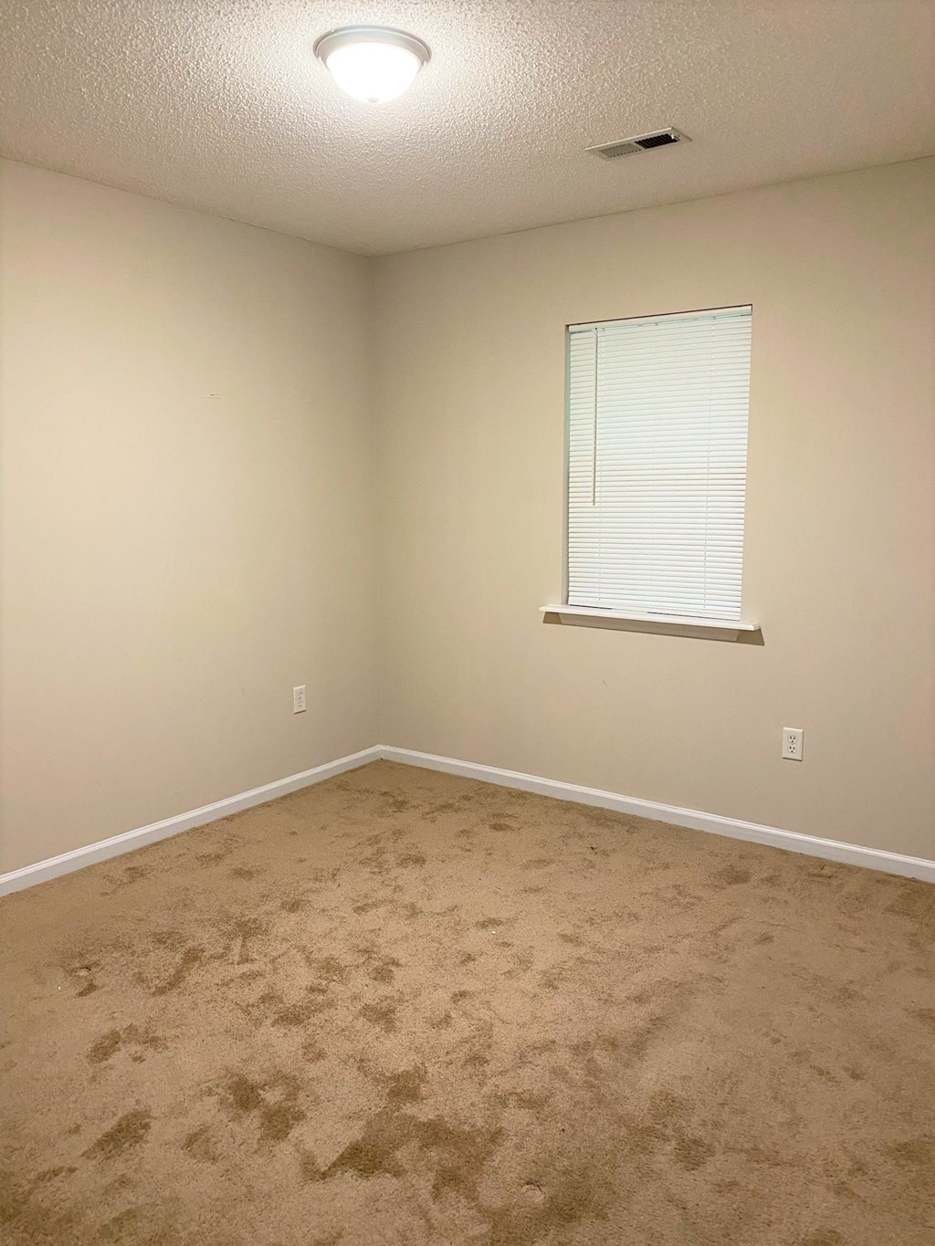 a empty room with a window and carpet