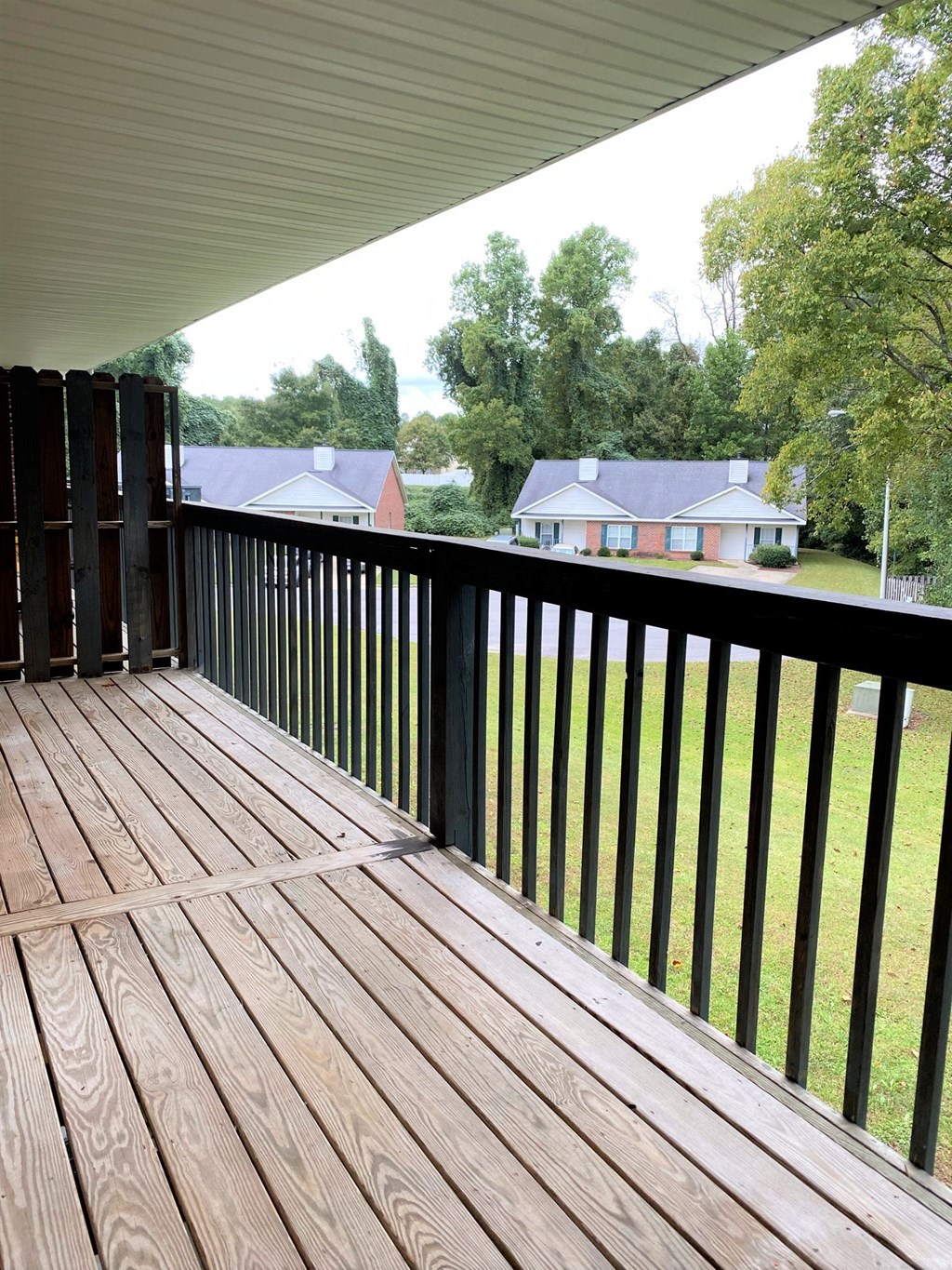 a deck with a view of a yard and a house