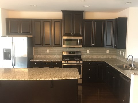 A kitchen with black cabinets and a granite countertop.