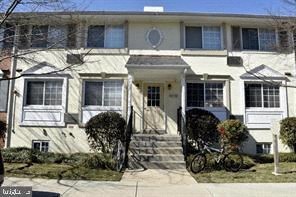 A white two-story house with a front porch and a bicycle parked in front.
