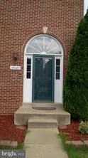 A white door with a glass window is set in a brick wall.