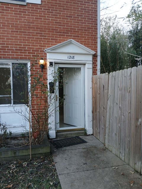 A red brick house with a white door and a wooden fence.