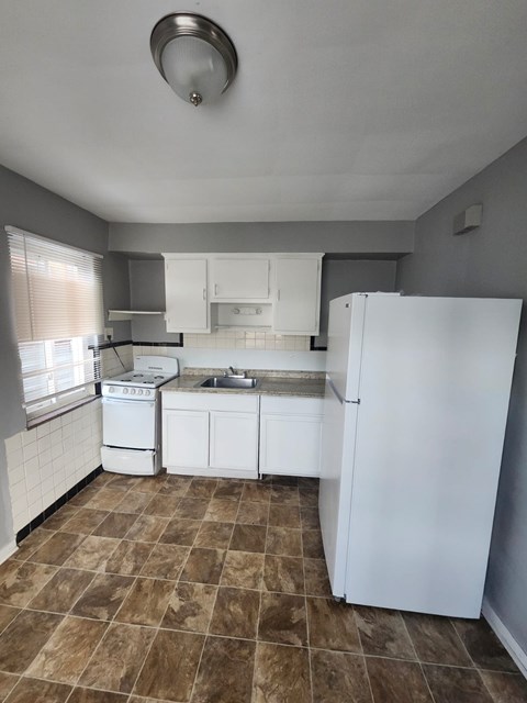 A kitchen with white appliances and brown tiles.
