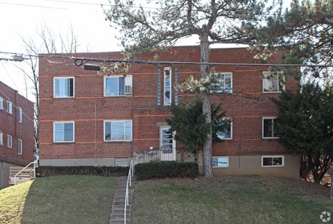A red brick building with a tree in front of it.