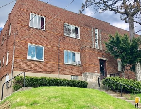 A red brick building with a tree in front.