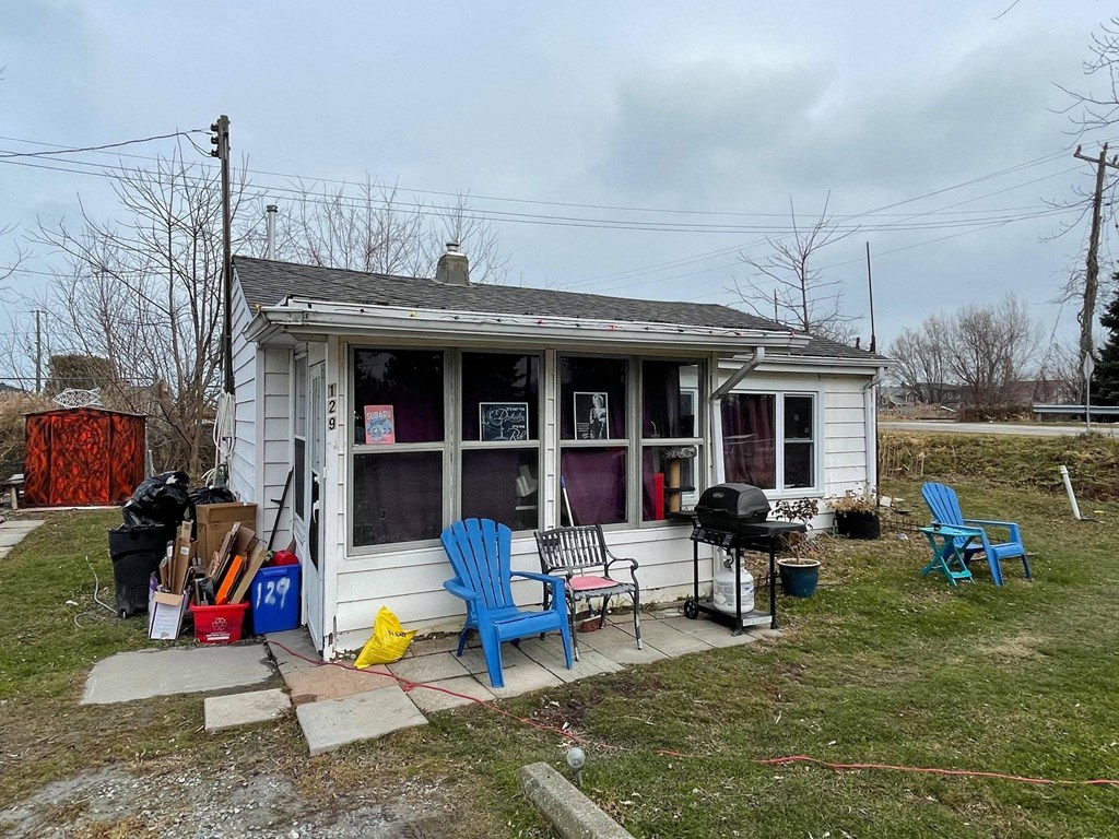 A small white house with a porch and a blue chair.