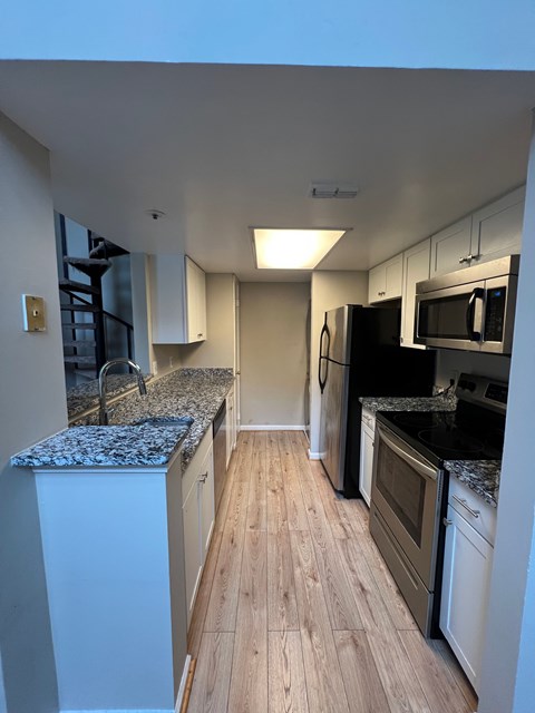 A kitchen with white cabinets and a granite countertop.