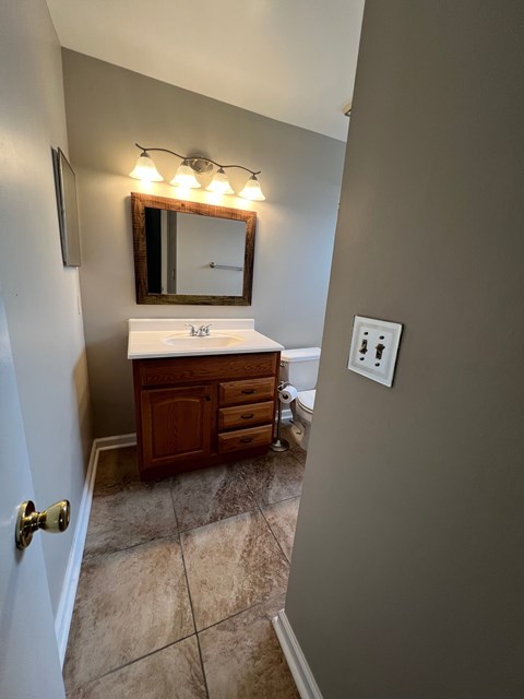 A bathroom with a sink, mirror, and light fixture.