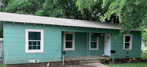a green house with a tree in front of it