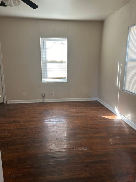 an empty room with wooden floors and a window