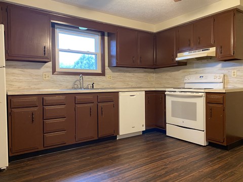 A kitchen with brown cabinets and white appliances.