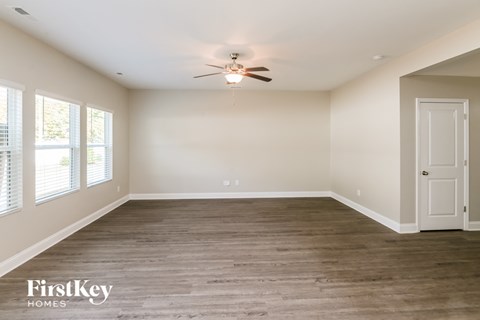 A spacious room with a ceiling fan and wooden flooring.