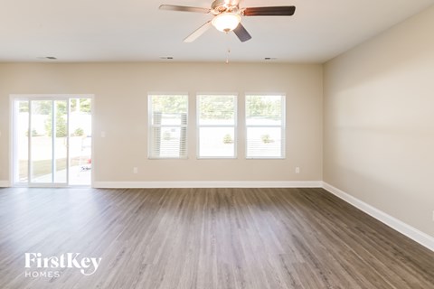 A spacious room with a ceiling fan and wooden flooring.