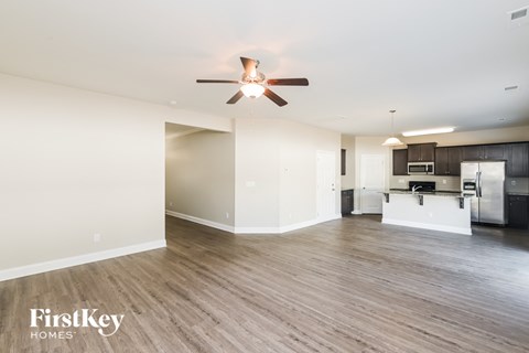 A spacious room with a ceiling fan and wooden flooring.
