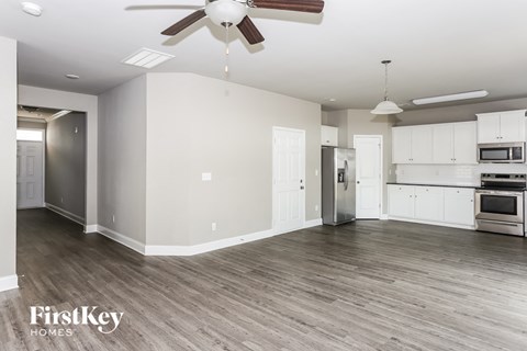 A spacious kitchen with white cabinets and a wood floor.